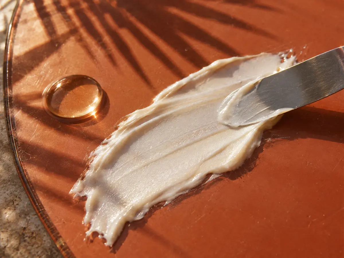 Pearly emulsion and a clear oil droplet spread across terracotta glass