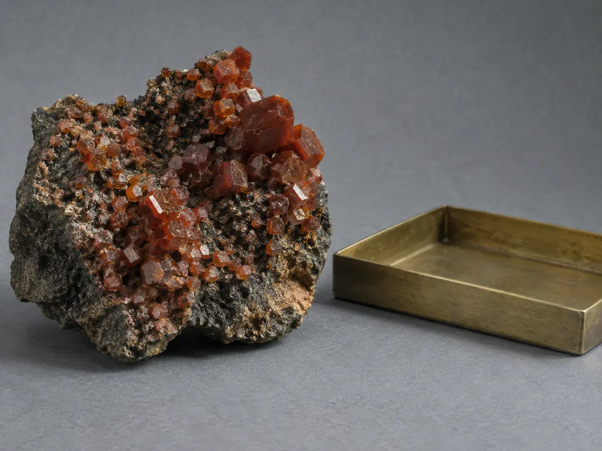 Dark vanadinite mineral specimen with muted orange-red crystals